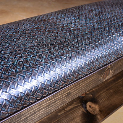 Closeup of silver-blue basketweave embossed leather cushion on Western wood bench with piping detail