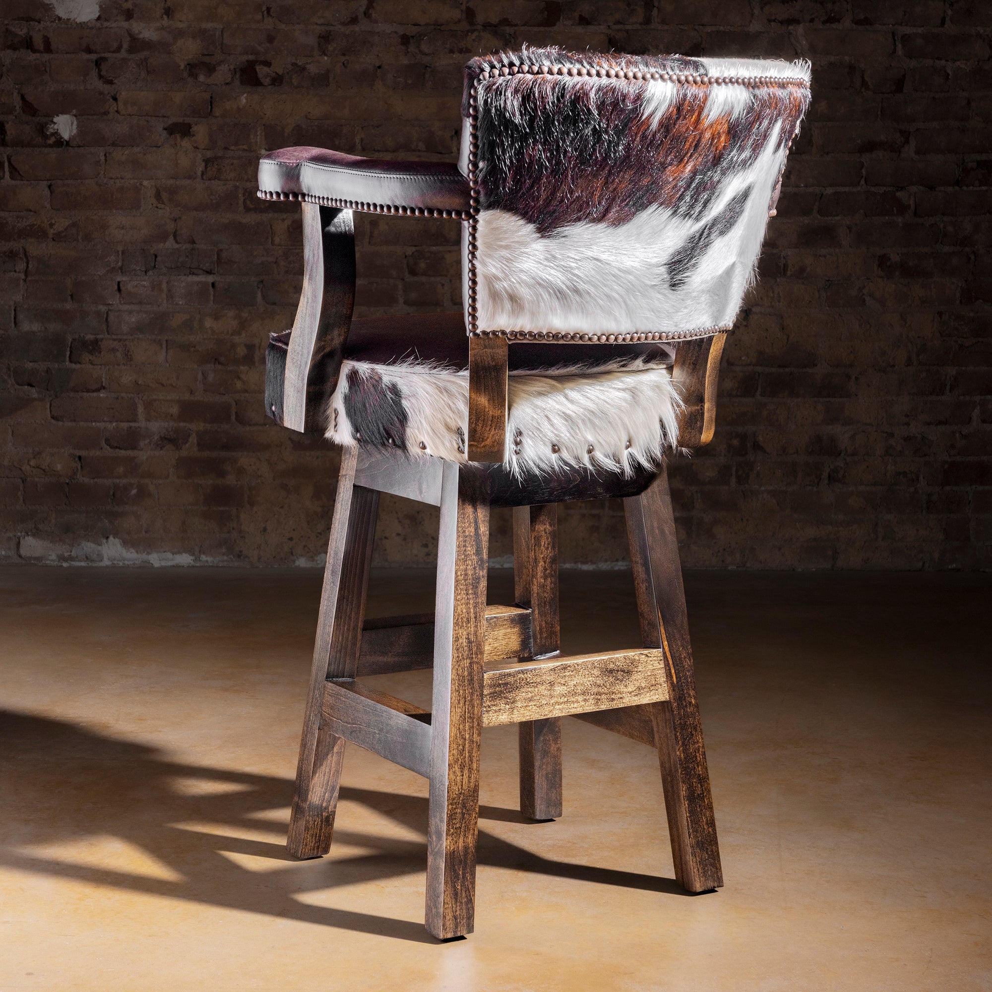 Back view of Cochise tricolor cowhide bar stool showing Brazilian cowhide panel, nailhead border, and Alder wood frame