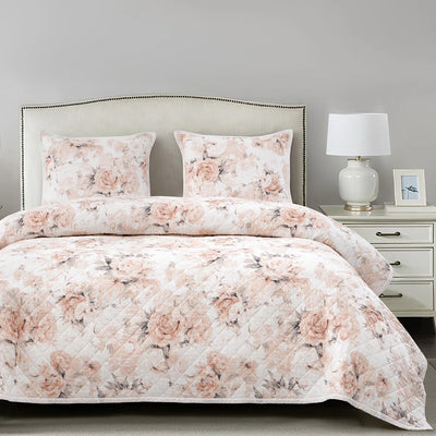 Colette reversible Western quilt set with blush rose floral print on vintage white, shown with matching sham in a sunlit bedroom.
