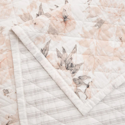Closeup of Colette quilt corner showing diamond quilting, blush floral print, and gray ticking stripe reversible backing.