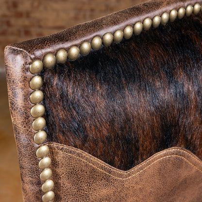 Closeup of cowhide yoke detail and nailhead trim on Western dining chair, leather-and-hide dining room chair texture