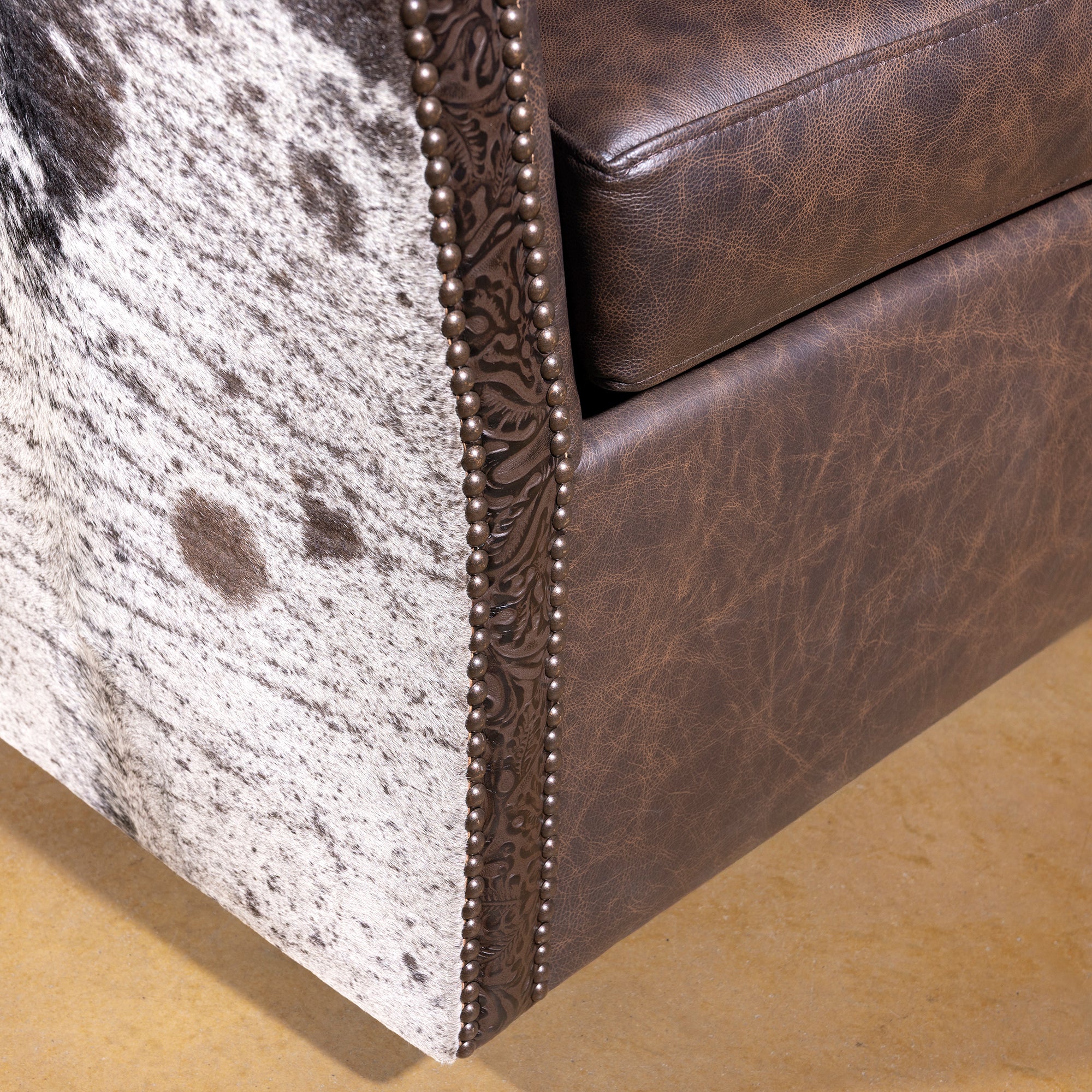 Cowhide and nailhead trim detail on Conch Canyon Swivel Chair handcrafted western design