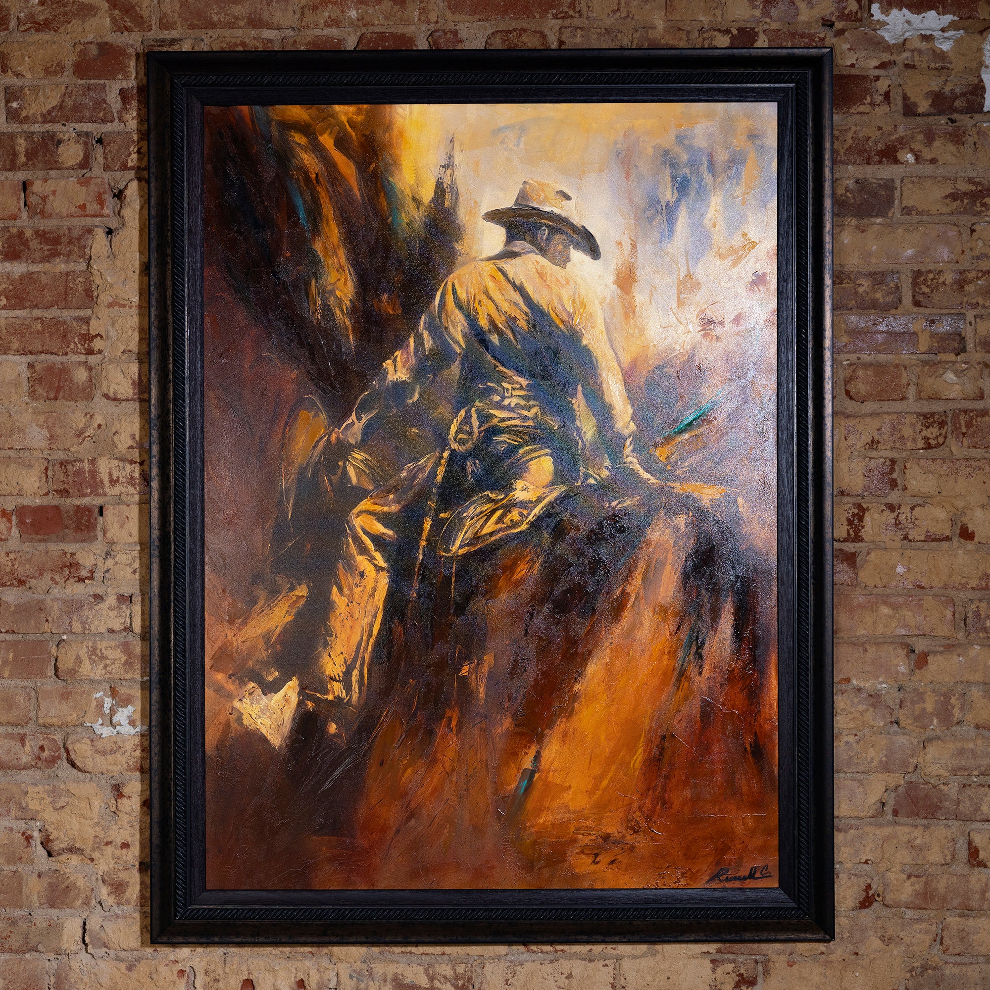 Framed Western oil painting of a cowboy on horseback resting on canyon ridge with warm gold and amber tones.