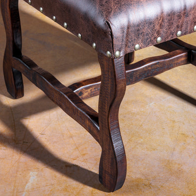 Detail of distressed microfiber nailhead trim, and sculpted wood legs on Western dining chair