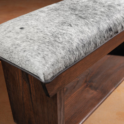 Corner view of cowhide bench with visible hide texture and stitching