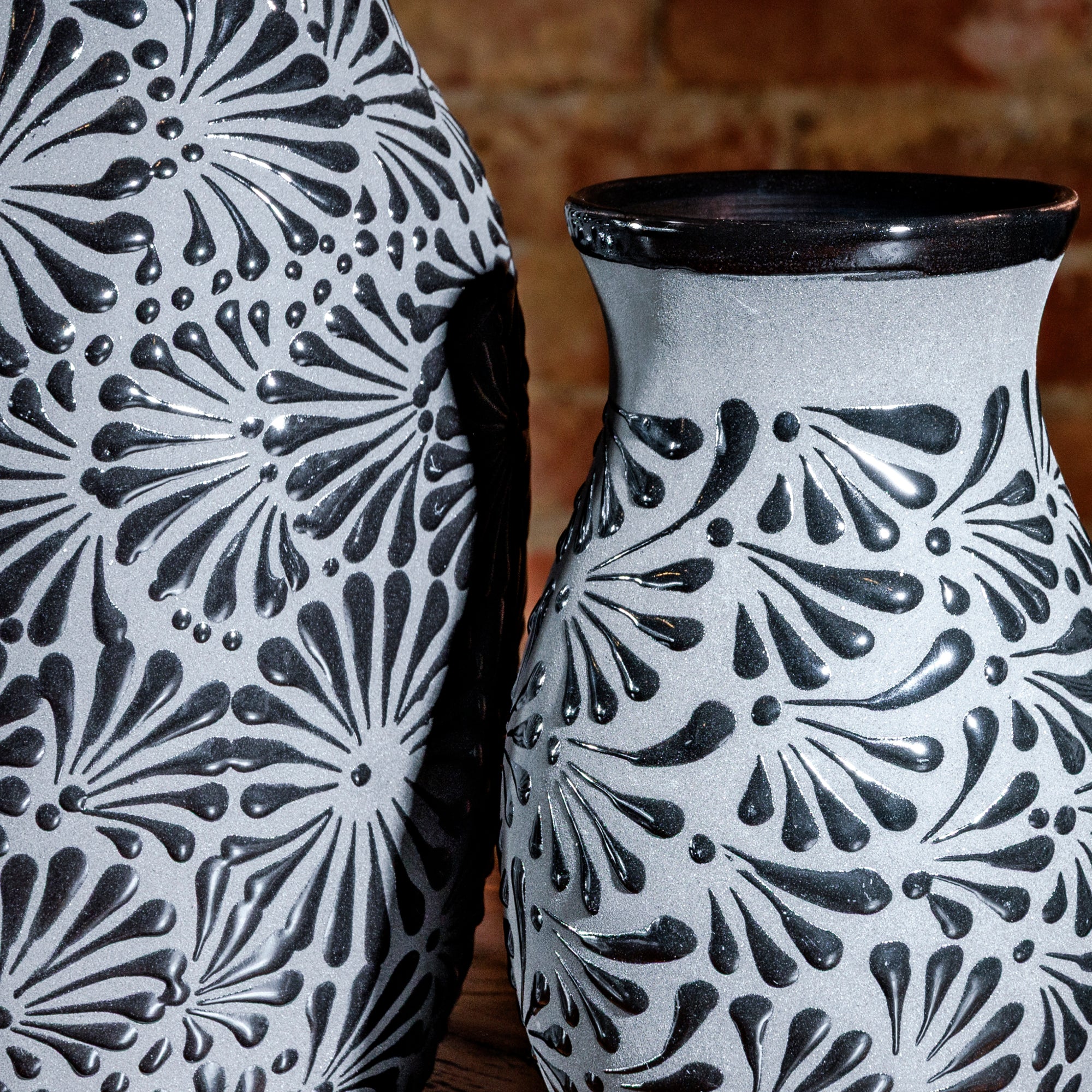Close-up of floral texture and glossy black rim on gray ceramic vase