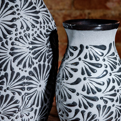 Close-up of floral texture and glossy black rim on gray ceramic vase