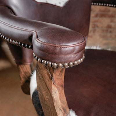 Close-up of the High Plains Luxe Swivel Stool armrest—brown leather with piping and nailhead trim for an elevated Western counter-height stool look.