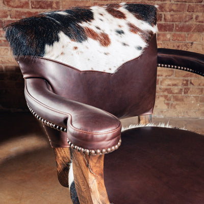 Detail of the High Plains Luxe Swivel Stool backrest—tricolor cowhide framed in brown leather, built to stand out in a Western bar or kitchen island.