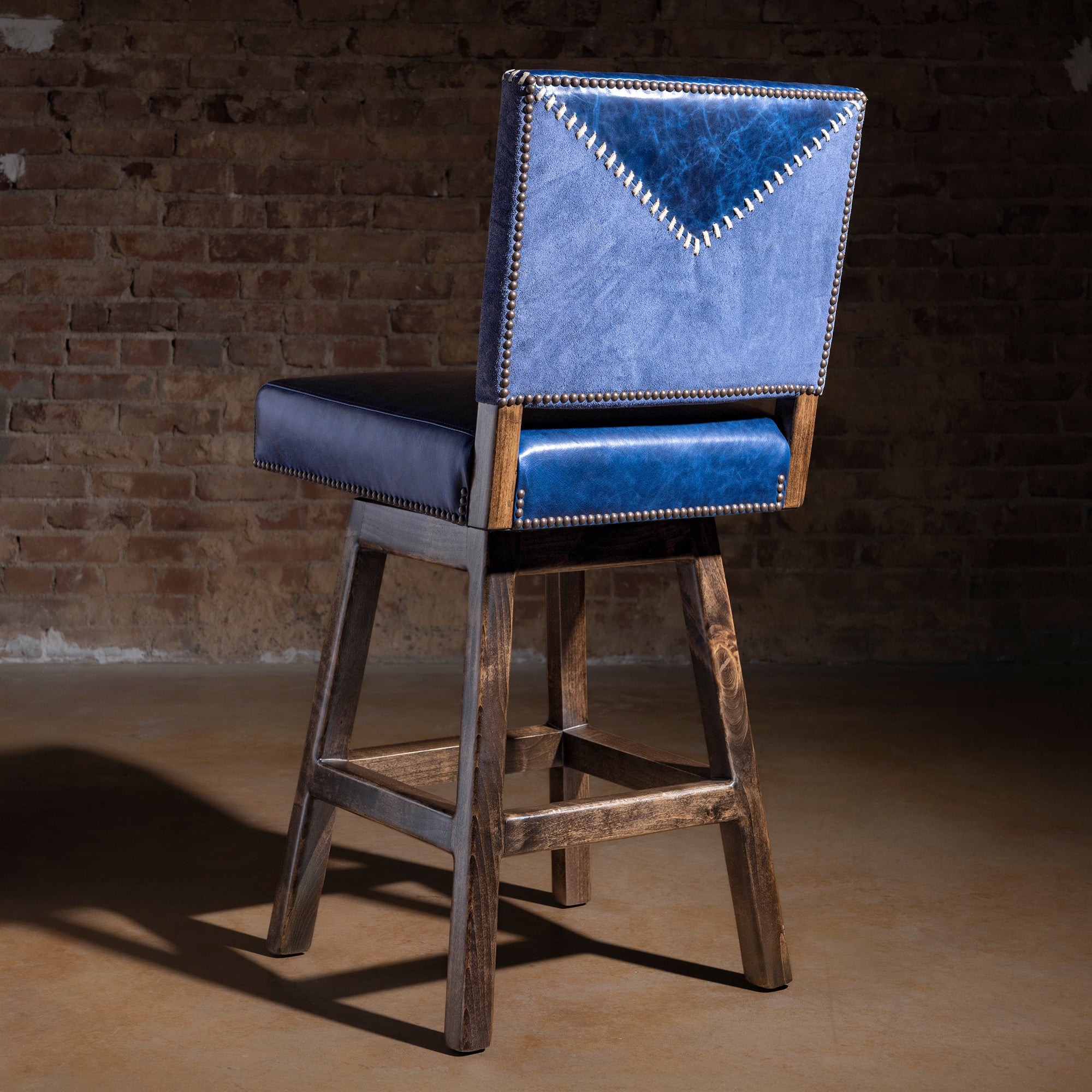 Back view of indigo yoke-stitched Western bar stool with suede panel, whipstitch detail, and nailhead border