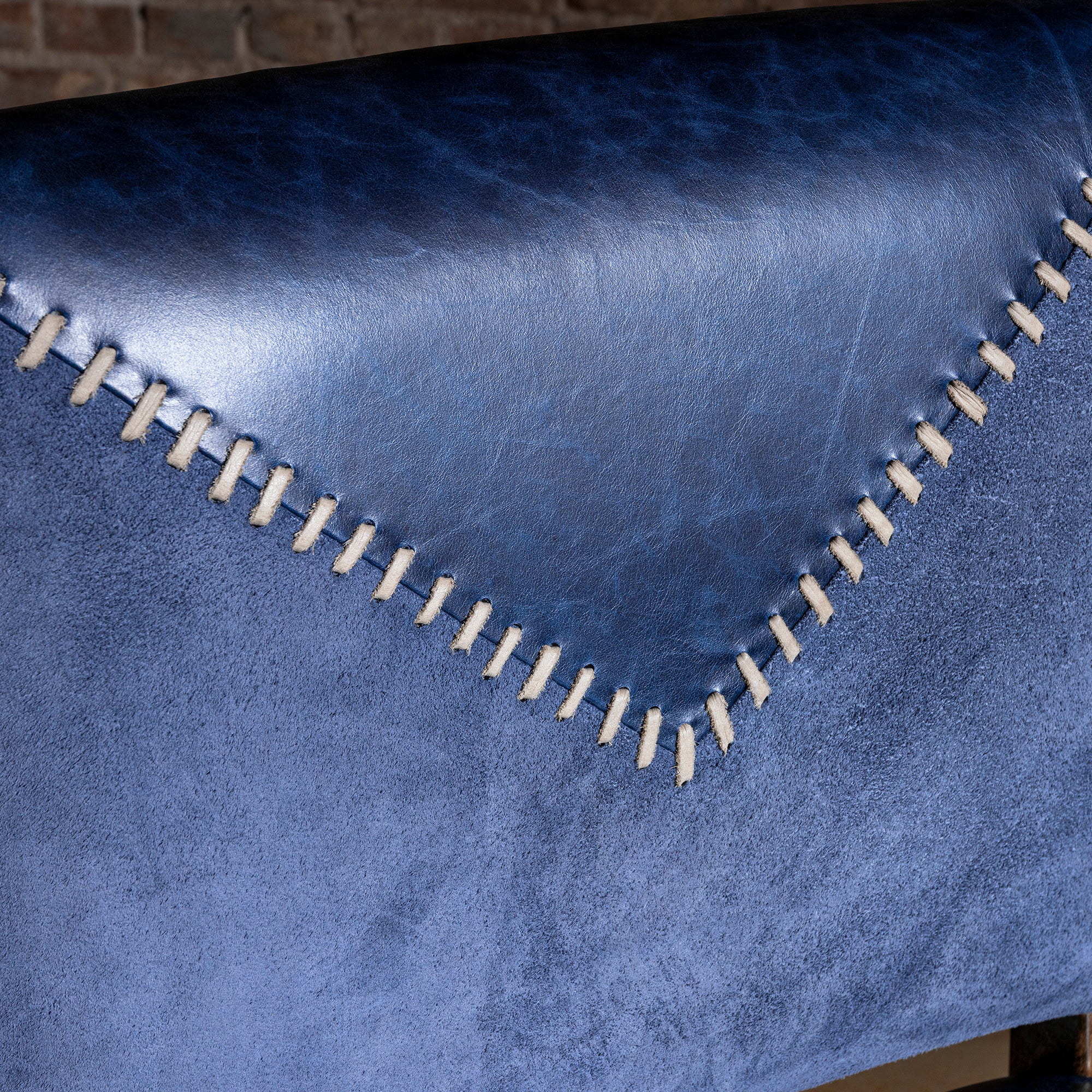 Closeup of indigo leather yoke with contrast whipstitching over suede back panel on armless Western bar stool