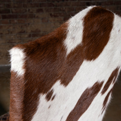 Close-up detail of Brazilian cowhide backrest on a Western dining chair with natural hide variation and rustic-luxe texture