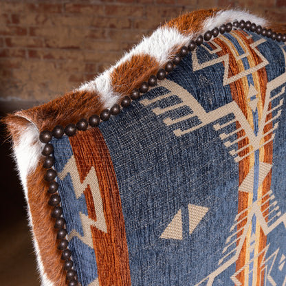 Close-up of blue Southwestern fabric backrest with dark nailhead trim and cowhide edge on a luxury Western dining chair