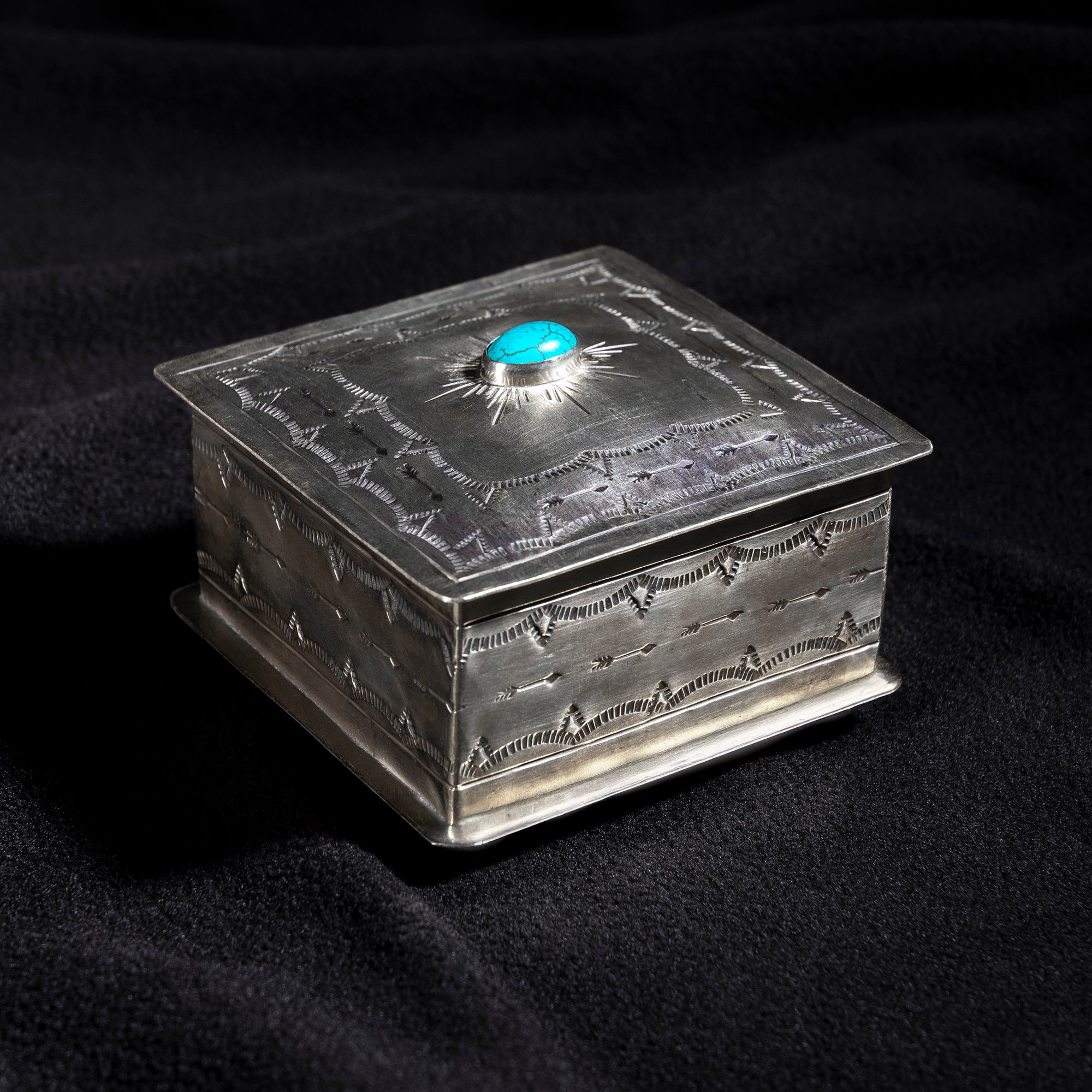 Handmade J. Alexander German silver box with turquoise cabochon sunburst design on dark fabric background