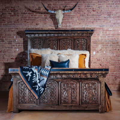 Hand-carved rustic western bed in rich wood with tall headboard and posts in a ranch bedroom