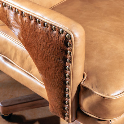 Close-up of cowhide inlay and hand-applied nailhead trim on leather armrest