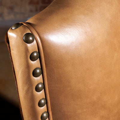 Antiqued nailhead trim on top-grain leather backrest with rich patina