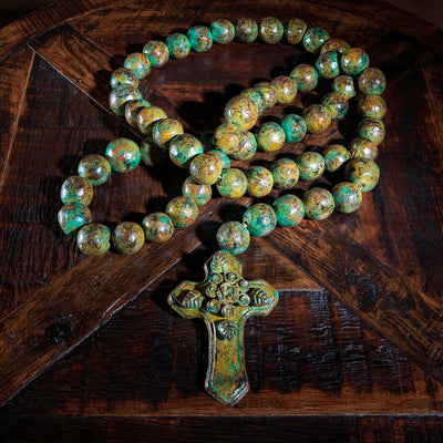 Large verdigris patina wall rosary displayed on rustic wood table