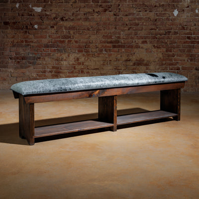 Long cowhide bench with dark wood base in rustic Western setting