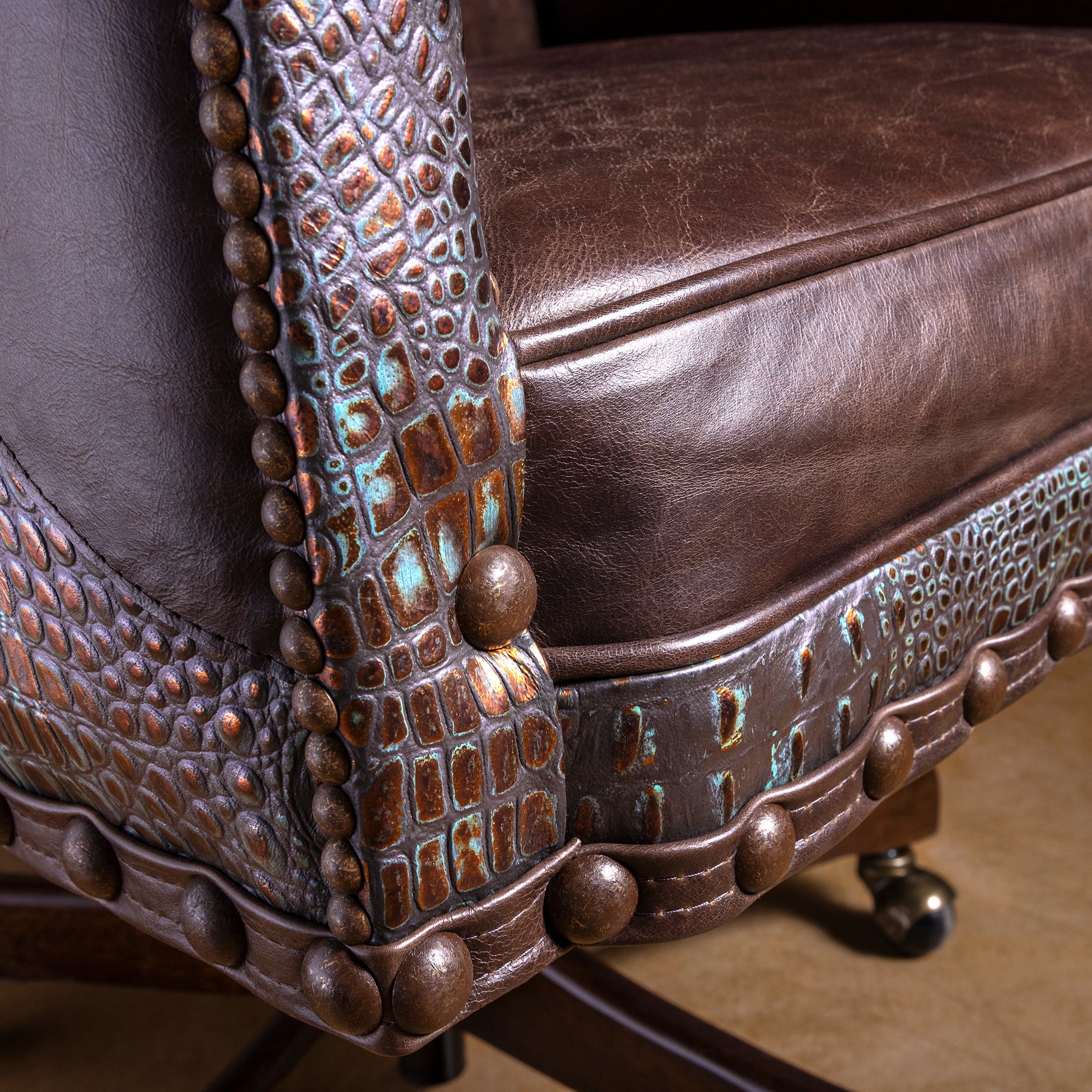 Close-up of croc-embossed leather accent on Western desk chair arm with turquoise patina and brass nailheads