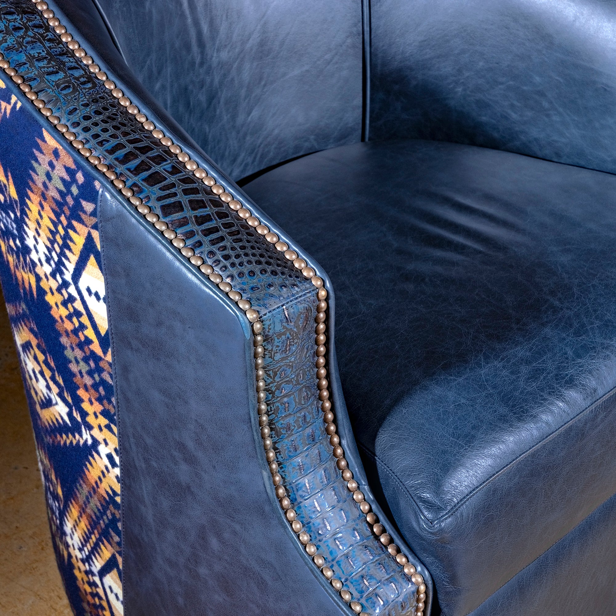 Midnight Caballero western swivel chair close-up with blue croc-embossed leather trim, antique nailheads, and distressed top-grain leather