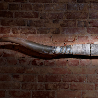Close-up of horn mount showing patina finish and leather wrap with brass nailheads