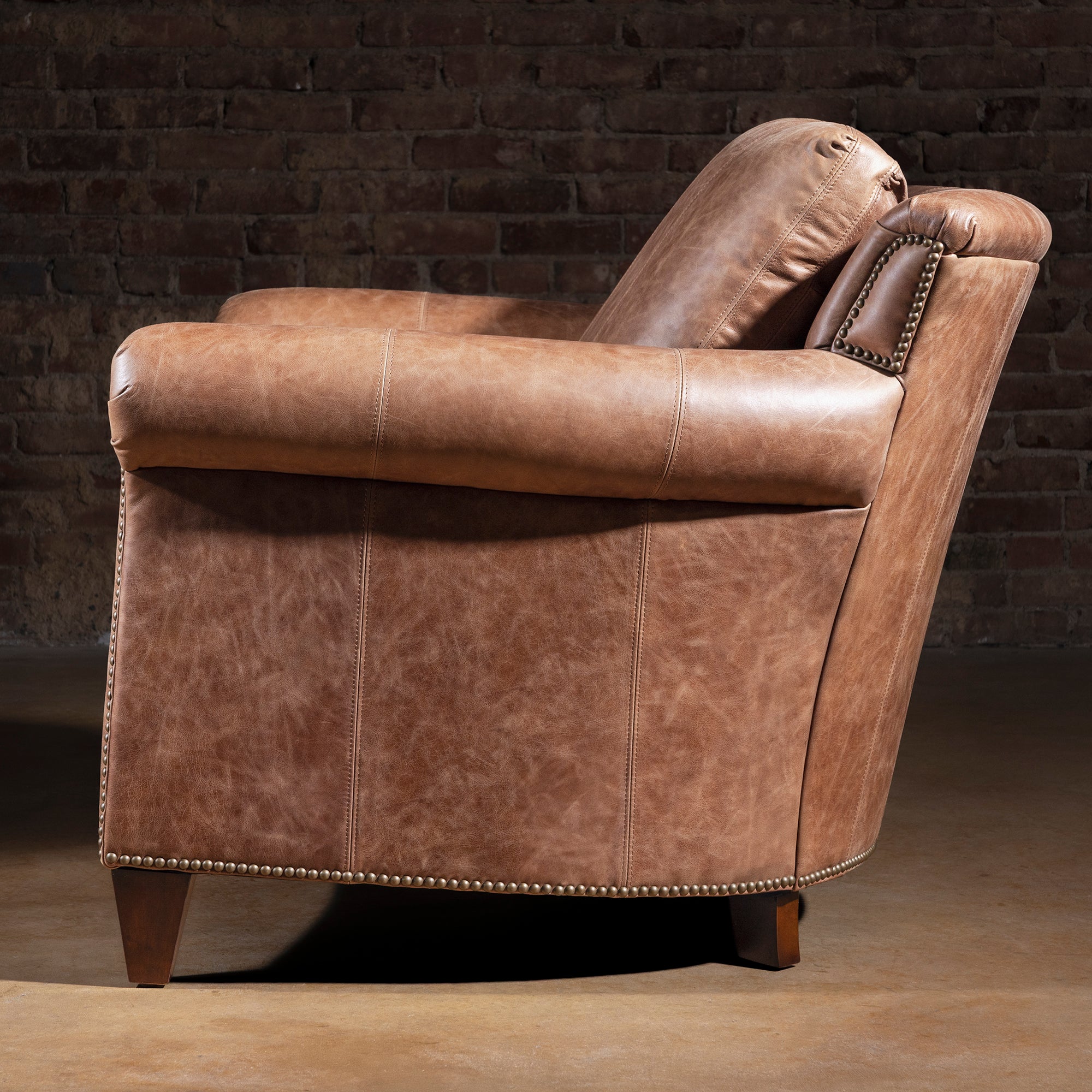Side profile of Oakley Frontier tan leather chair with curved back and rolled arms