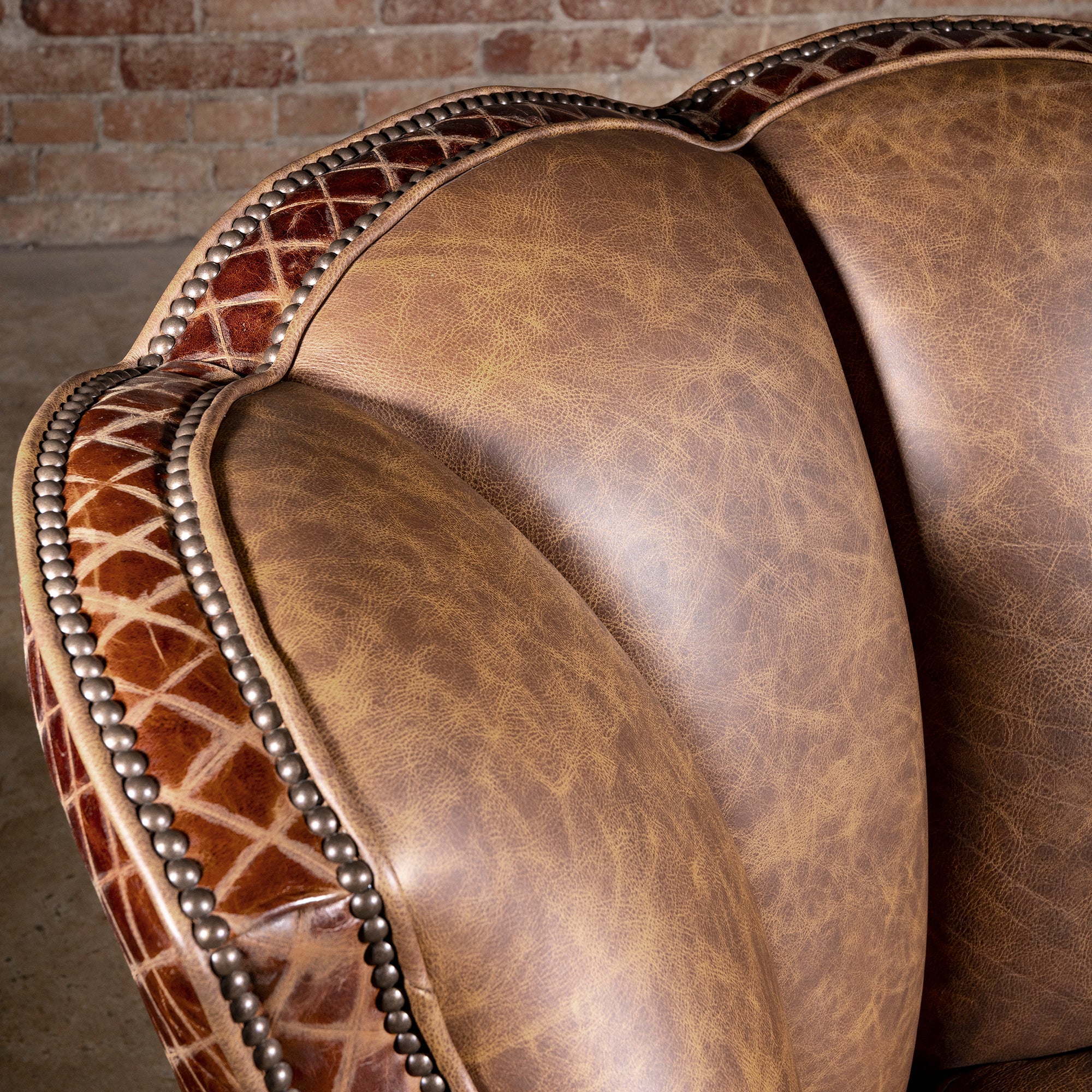Palacio Bronce Western Leather Swivel Chair detail with diamond-embossed leather, antique nailheads, piping, and curved crest.