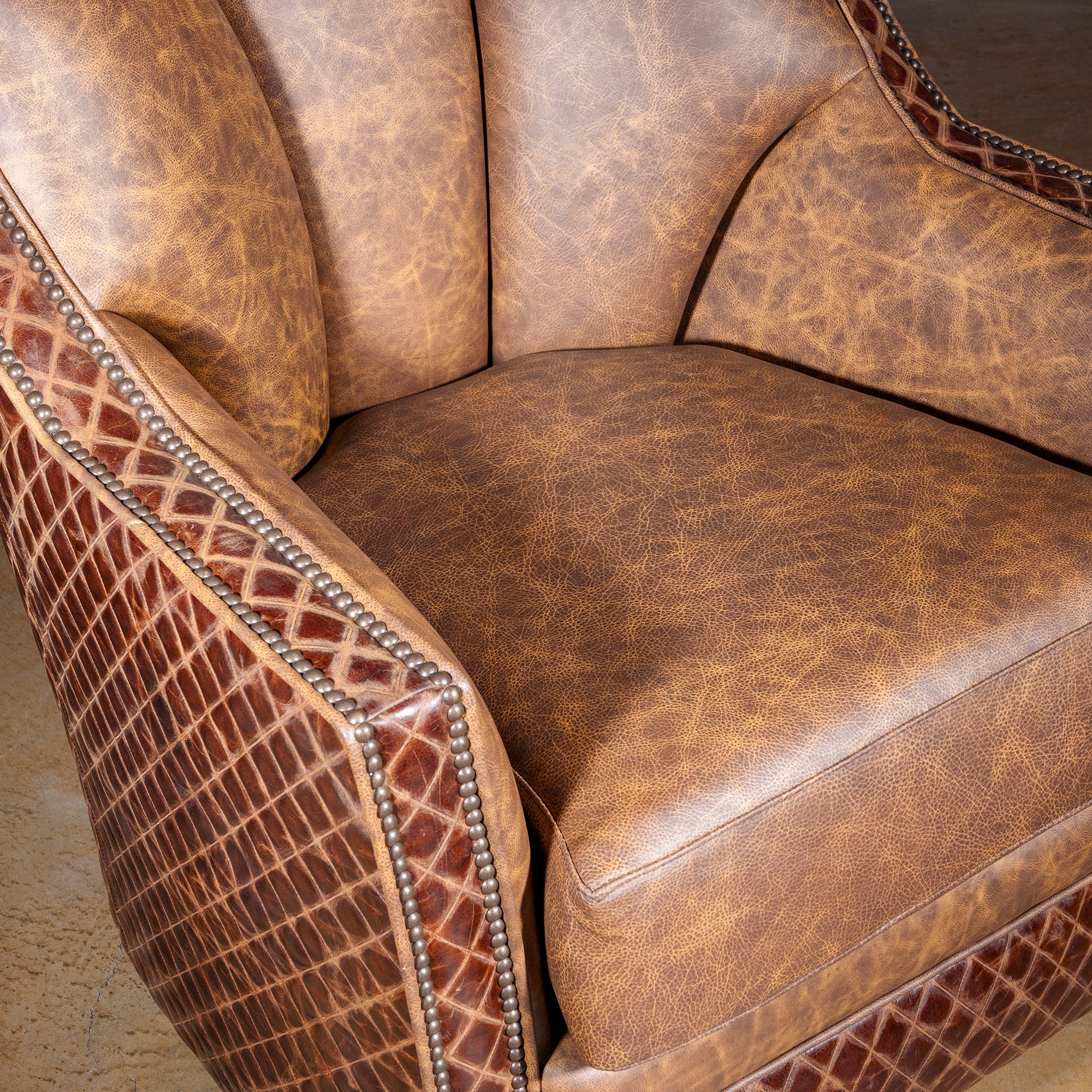 Palacio Bronce Western Leather Swivel Chair close-up showing burnished leather seat, embossed trim, antique nailheads, and high back.