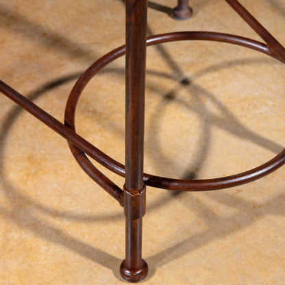 Close-up of forged iron legs and circular footrest ring on copper and iron Western bar stool
