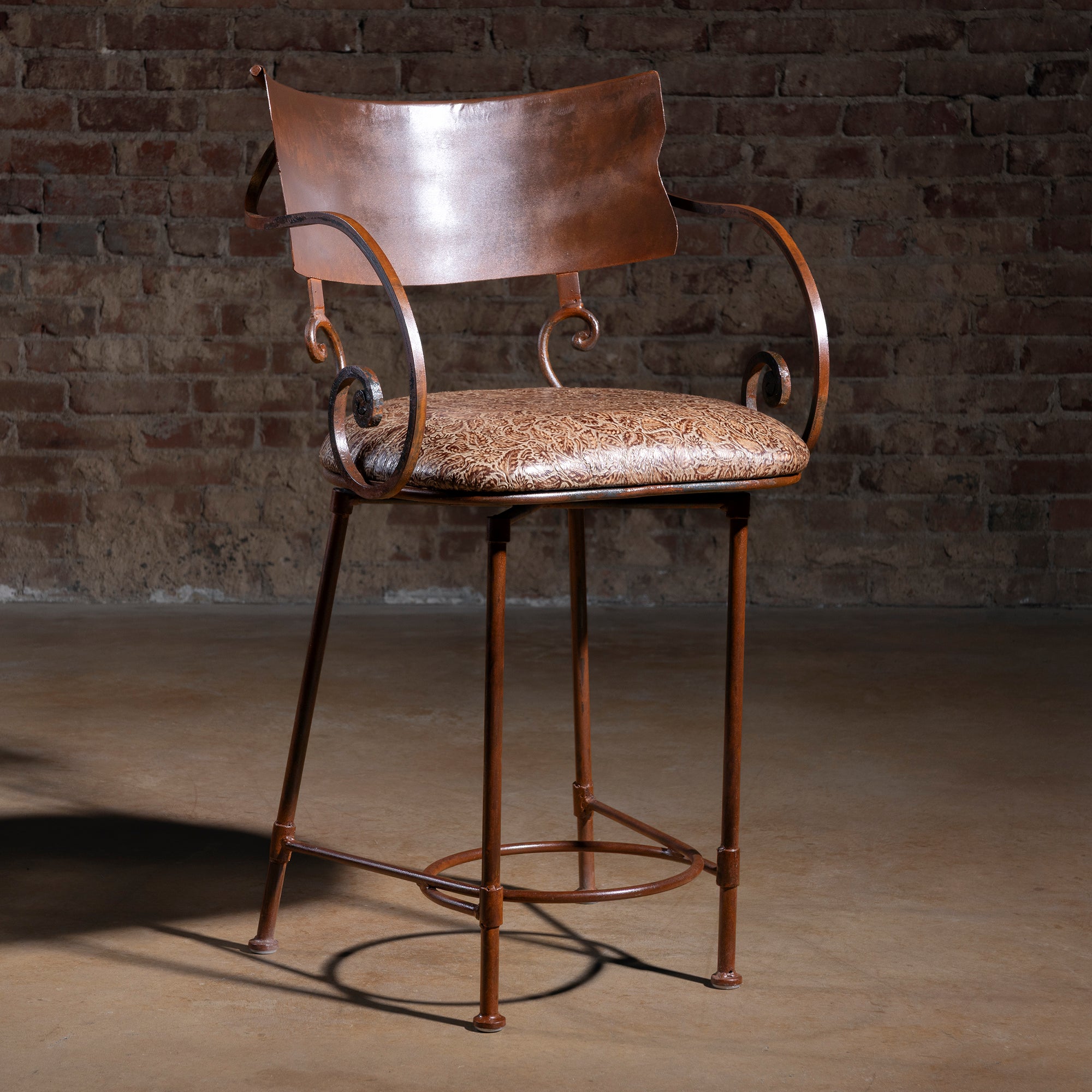 Western iron bar stool with copper-toned backrest, scroll arms, and tooled leather seat cushion