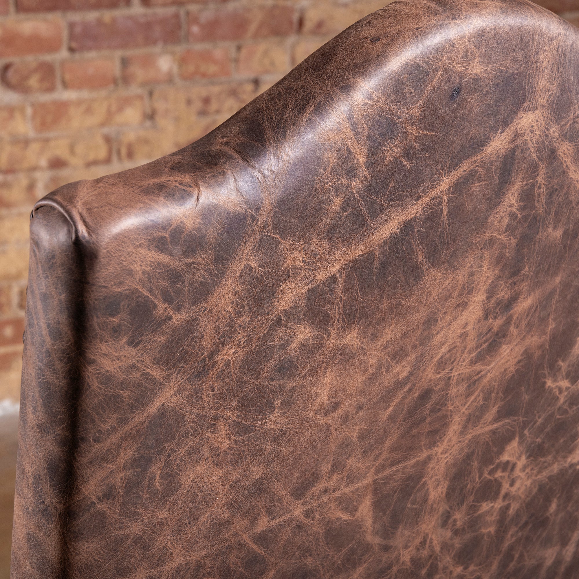 Closeup of distressed brown top grain leather on Pecos Canyon high back dining chair
