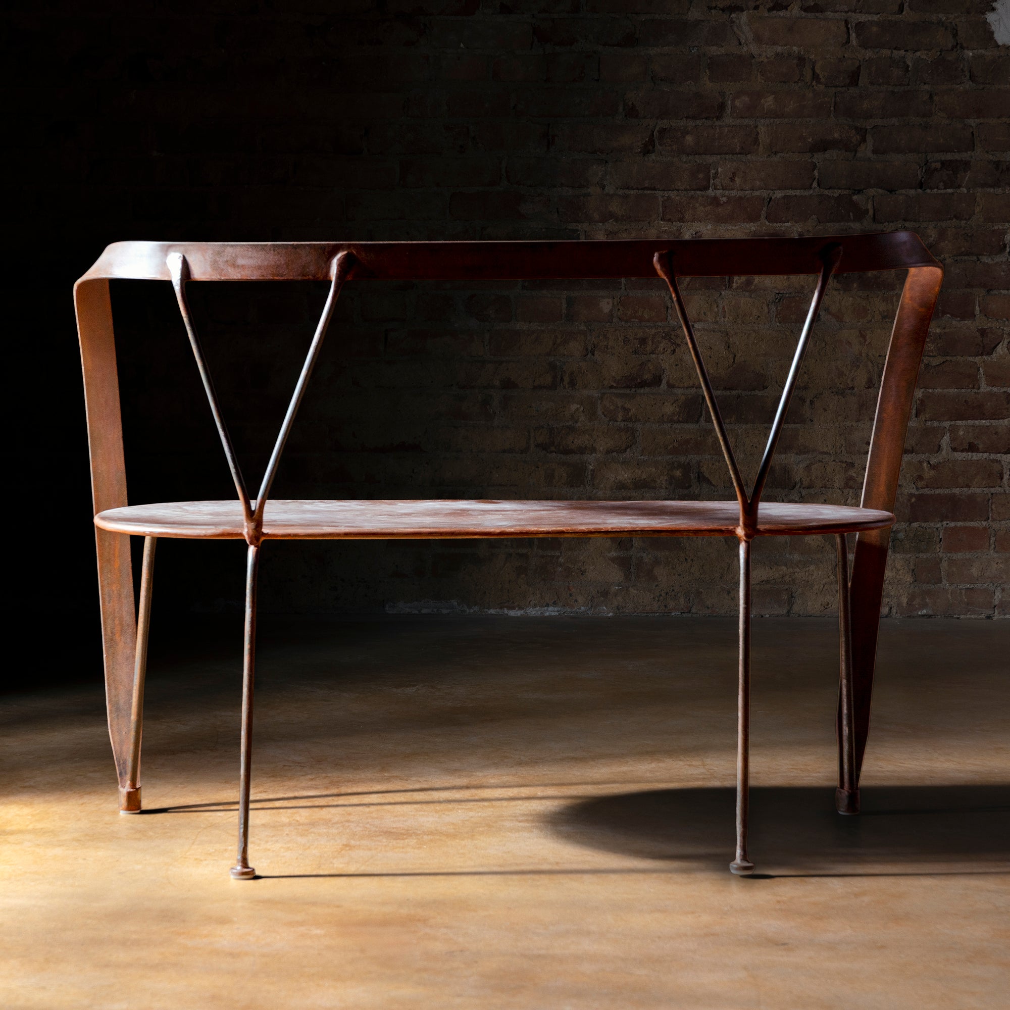 Railspur Gallery Bench back view showing hand forged Western iron frame against brick wall