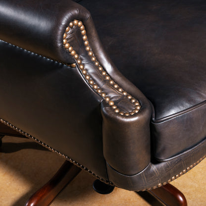 Close-up of leather desk chair arm with antique nailhead trim and rich dark brown leather upholstery.