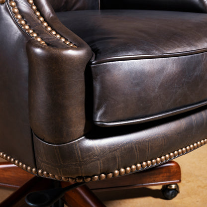 Close-up of leather seat cushion and nailhead base trim on swivel executive desk chair with rolling casters.