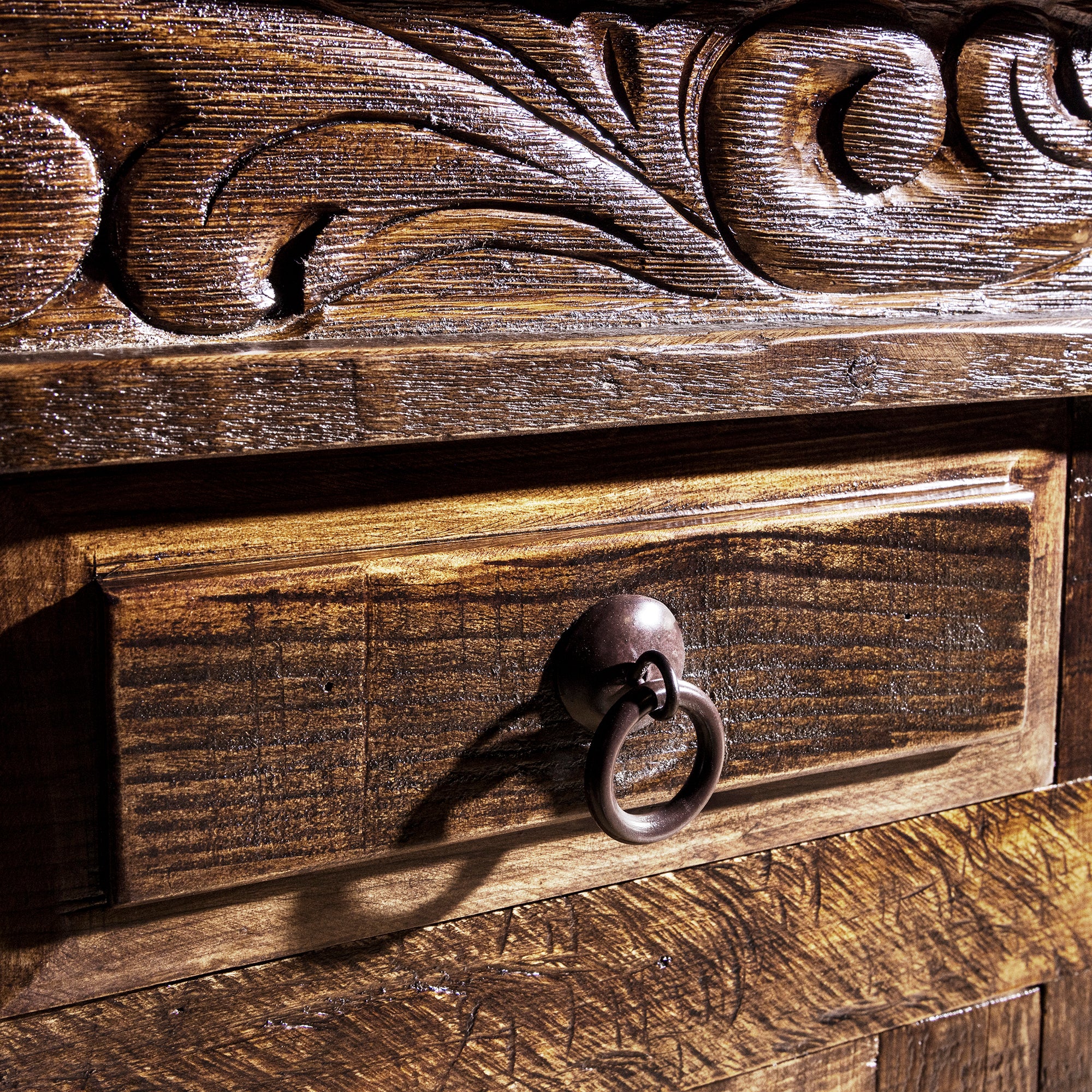 Ring-pull drawer hardware close-up on reclaimed wood carved Western buffet