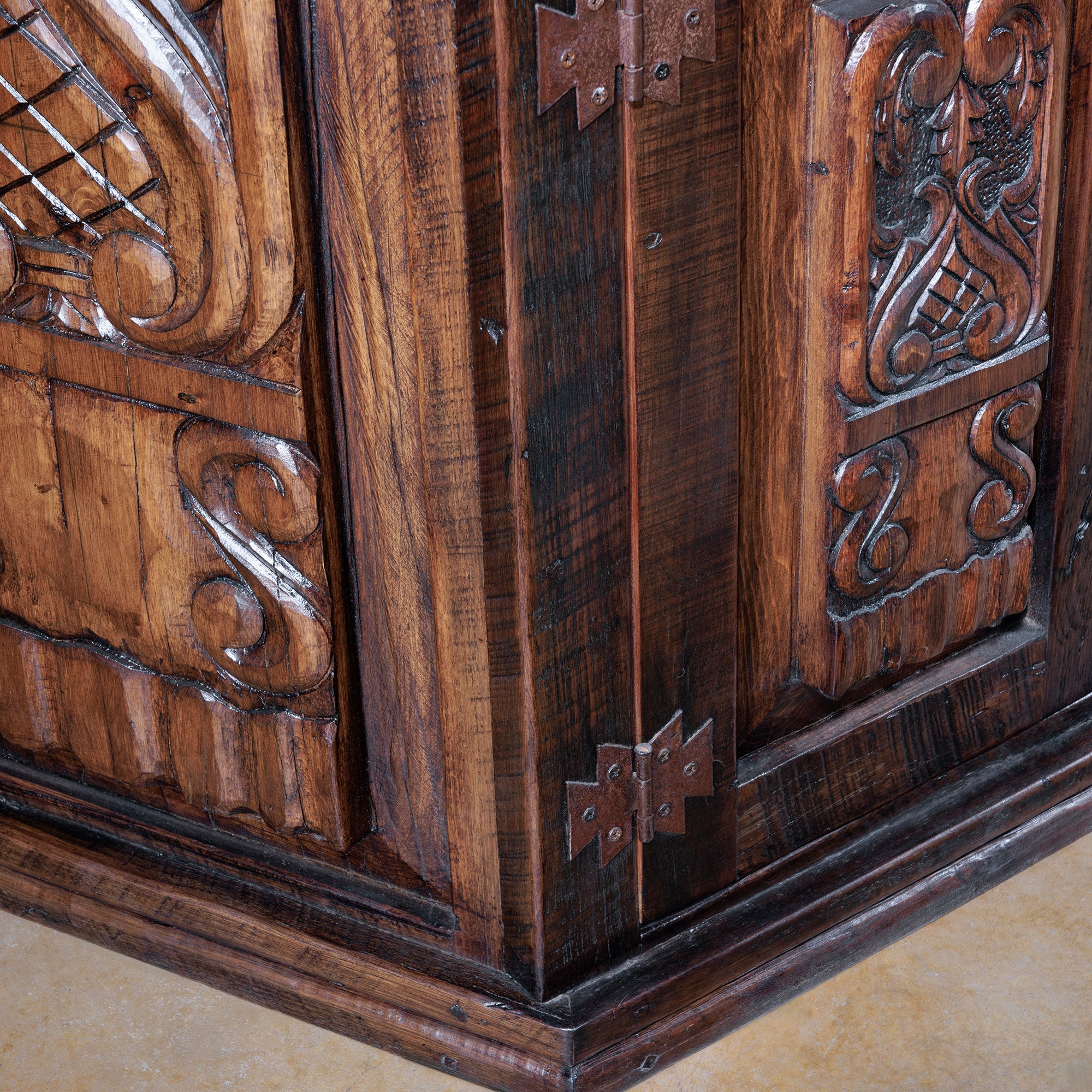 Corner detail of rustic wood buffet with carved panels and dark wood grain