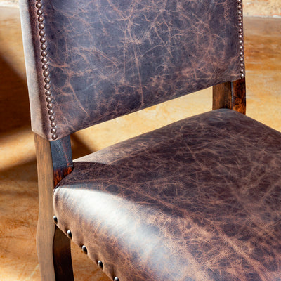 Distressed leather seat and nailhead detail on Western chair