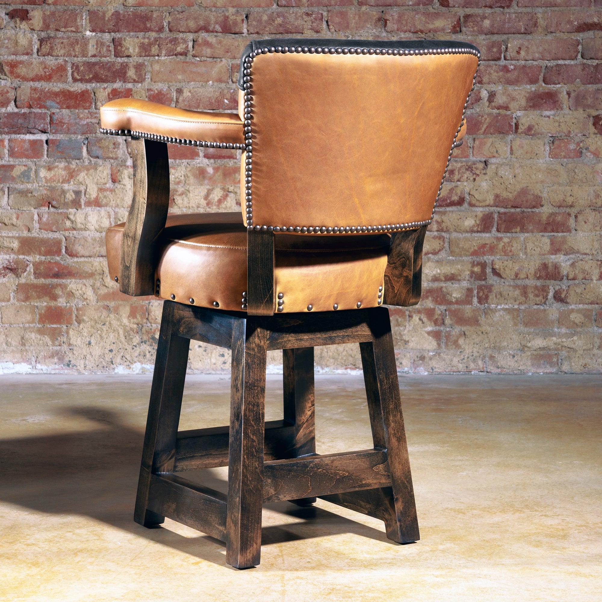 Rear view of The Santiago Swivel Bar Stool showcasing midnight black leather yoke over whiskey leather backrest