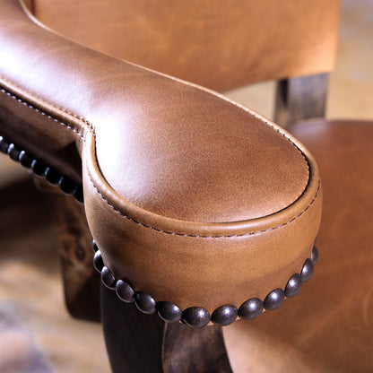 Close-up of sculpted leather armrest with antique nailhead trim on The Santiago Swivel Bar Stool