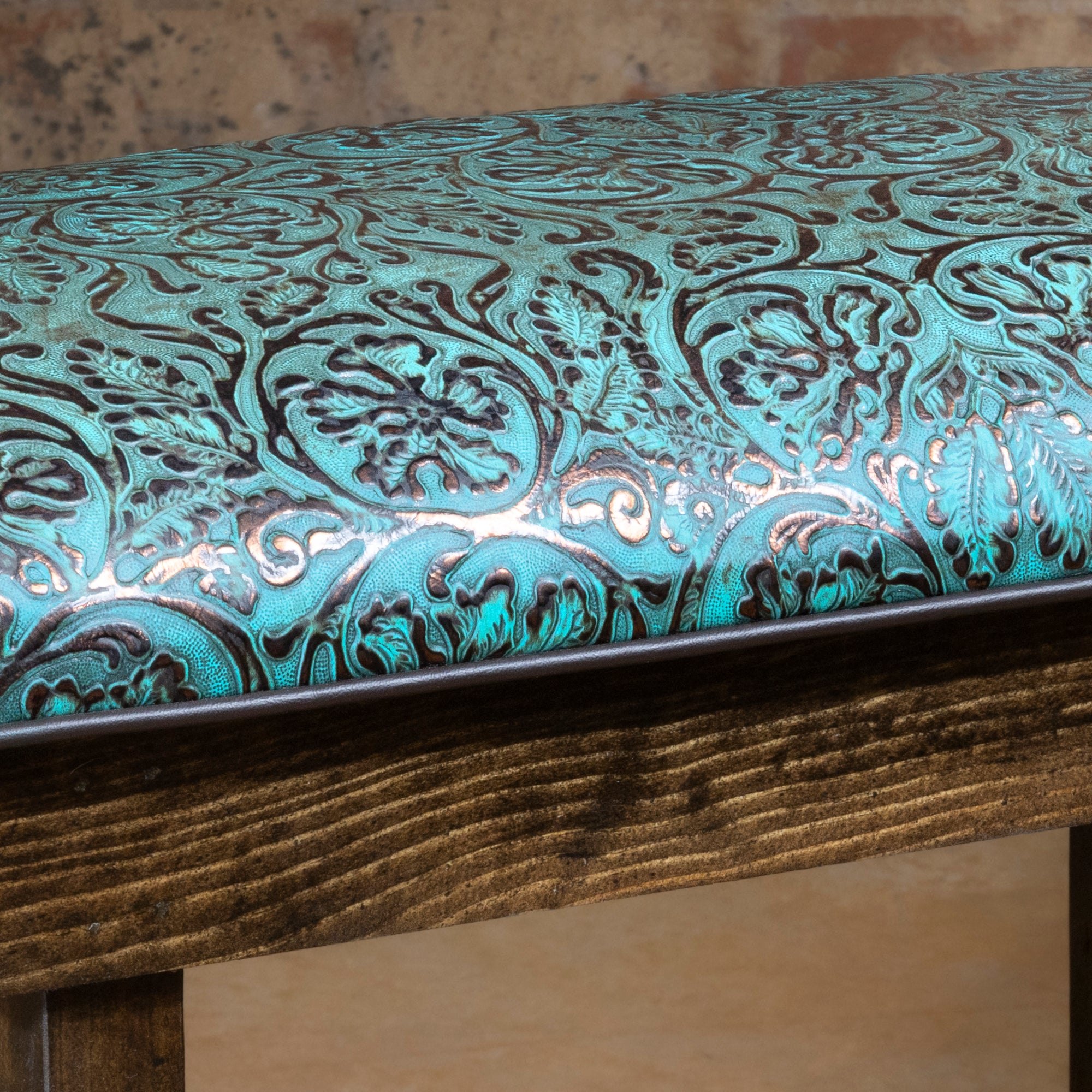 Closeup of turquoise tooled leather cushion on Western bench showing floral tooling detail and edge finish