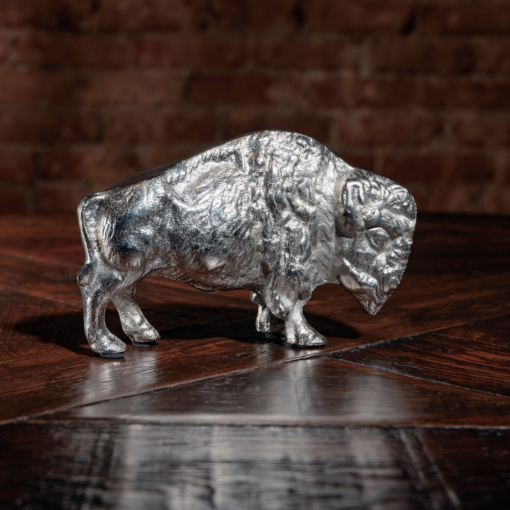 Silver buffalo sculpture on rustic wood surface