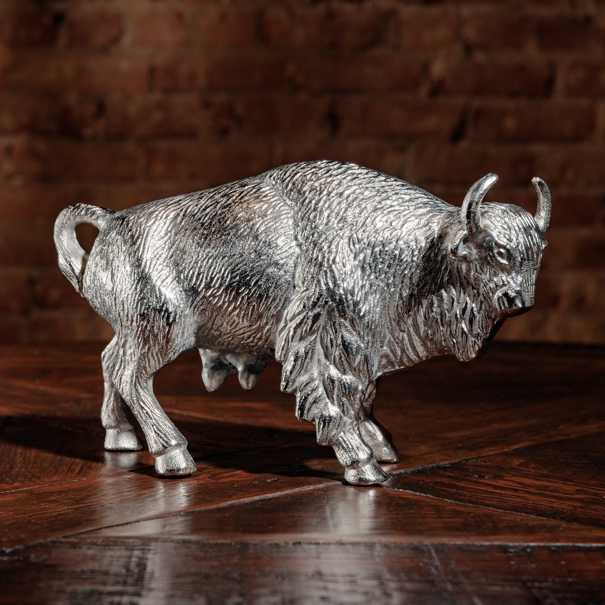 Silver bull sculpture on wood table with brick wall background