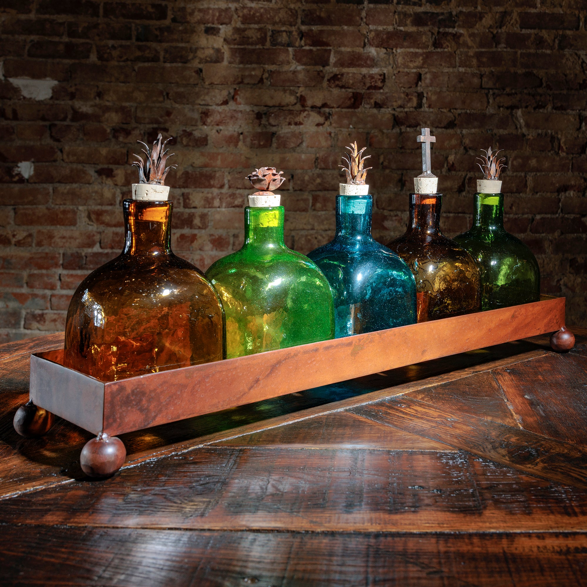 Angled side view of multicolored glass bottles in tray showing detailed stoppers