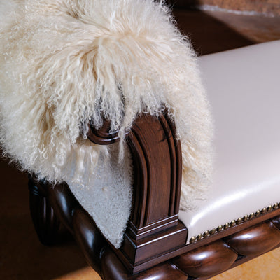 Close-up of rolled wooden arm with ivory Tibetan lamb upholstery