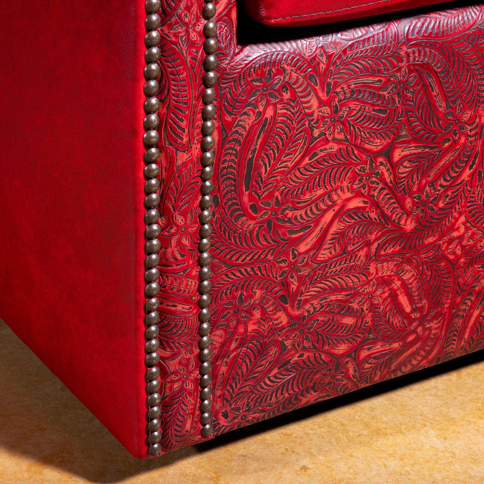 Base panel tooling and nailhead detail on Vaquera Royale red tooled leather swivel chair