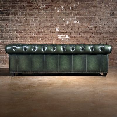 Verde Sovereign western sofa rear view with deep green leather panels, tufted back rail, nailhead trim, and dark wood feet