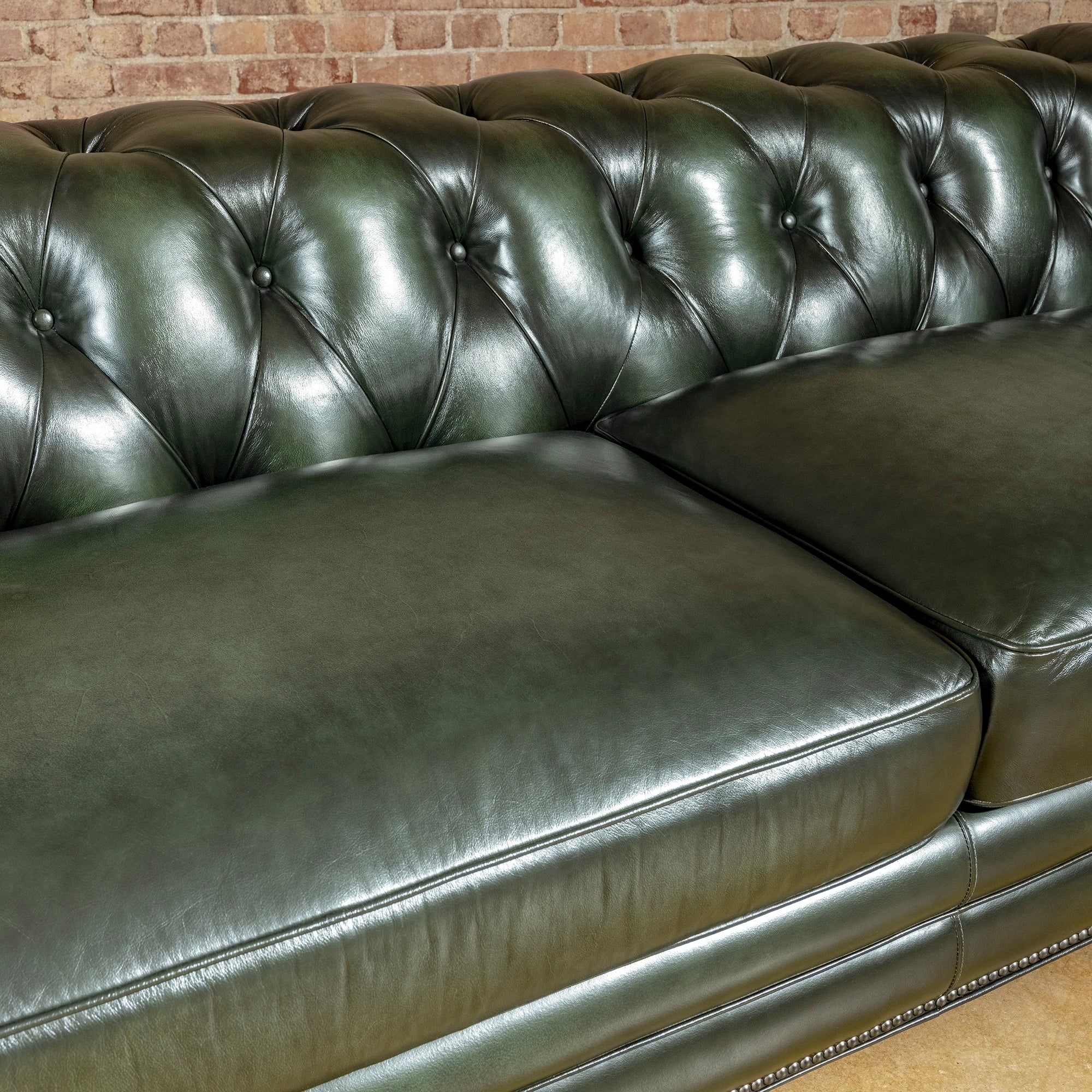 Verde Sovereign western sofa close-up showing deep button tufting, generous leather seat cushions, piping, and rich green tone