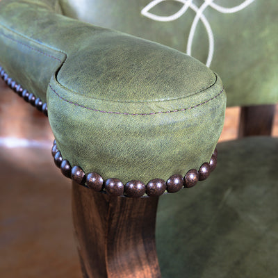 Detailed view of Western bar stool armrest with olive leather and hand-applied nailhead trim