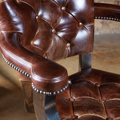 Close-up of the front seat on a Western bar stool showcasing rich brown leather and decorative nailhead trim